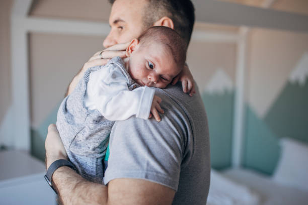 Father holding his baby boy in arms at home.