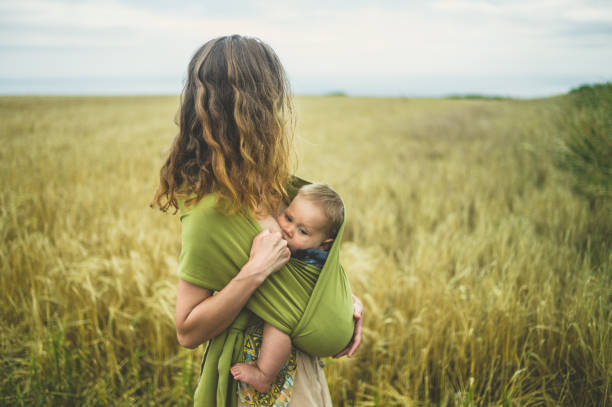 A young mother is breastfeeding her baby in a field